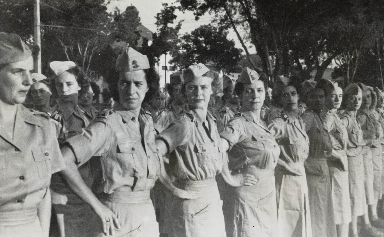 Zwart-witfoto van vrouwen in militair uniform opgesteld in formatie.