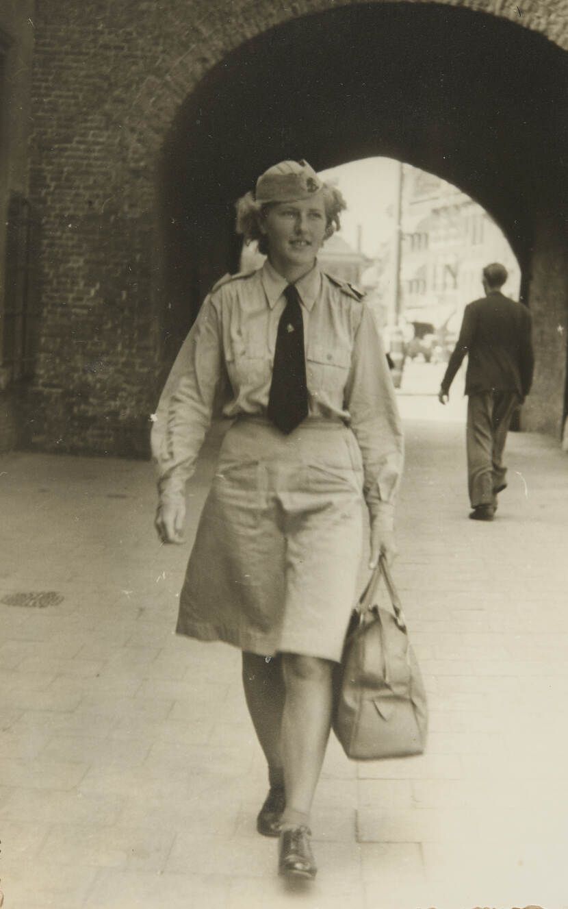 Zwart-witfoto van Goossens-Kortenhorst in militair uniform lopend door een straat, met tas in hand.