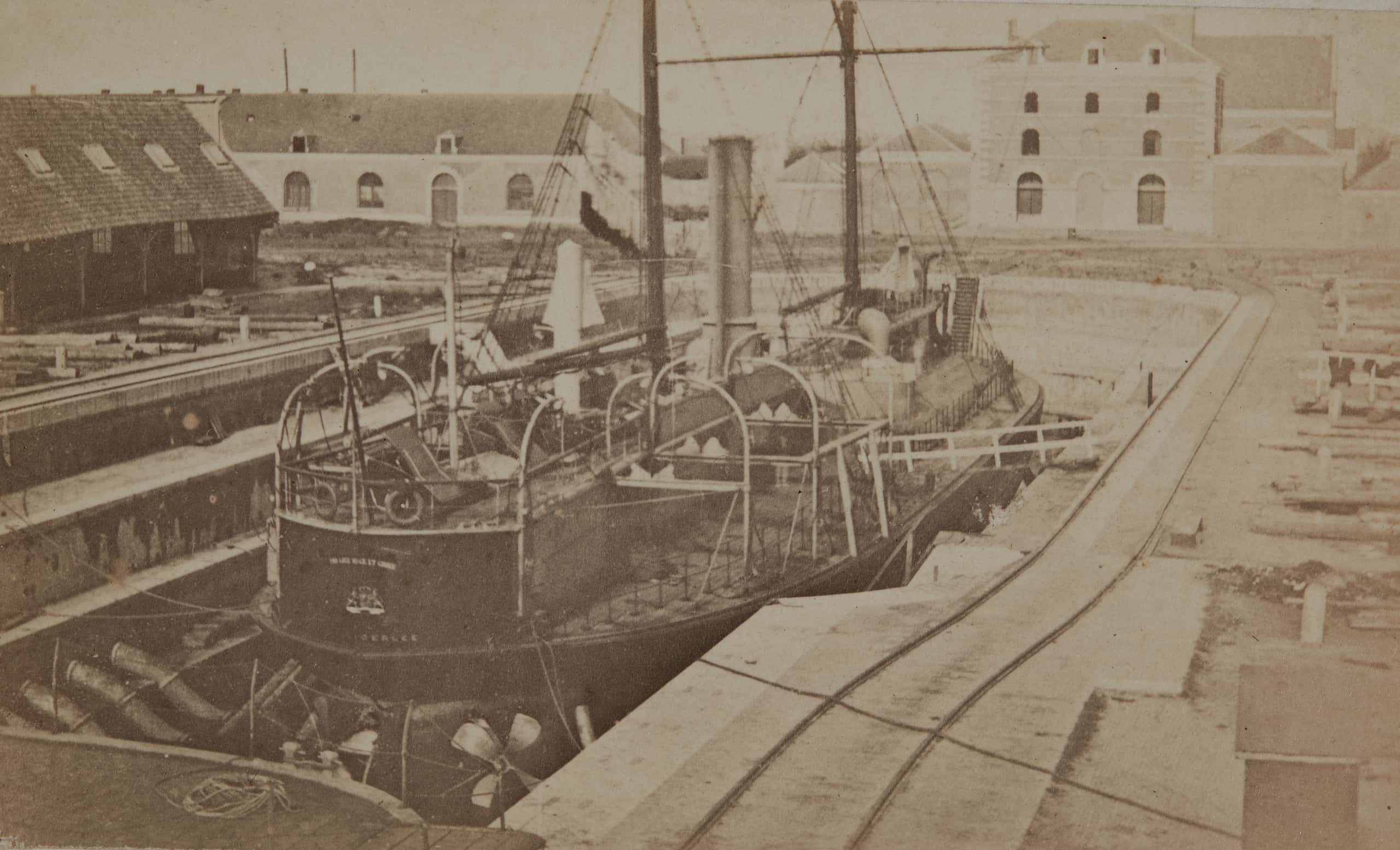 Zwart-witfoto. Een schip ligt aan de kade.