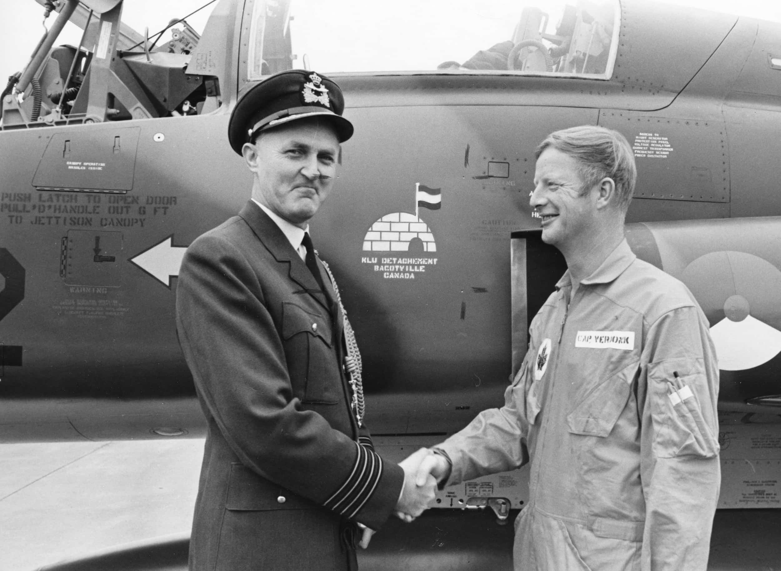 Zwart-witfoto. Twee mannen in militair uniform schudden elkaar de hand voor een vliegtuig.