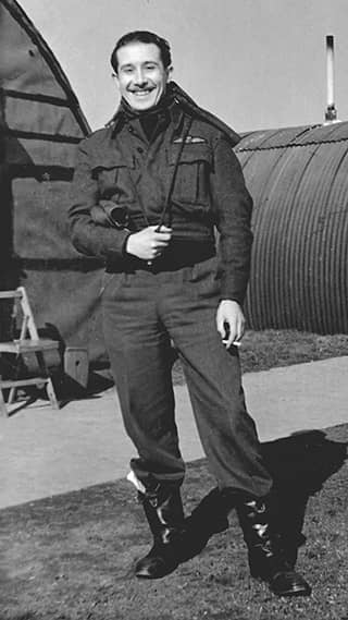 Zwart-witfoto van een man in militair uniform. Hij lacht naar de camera.