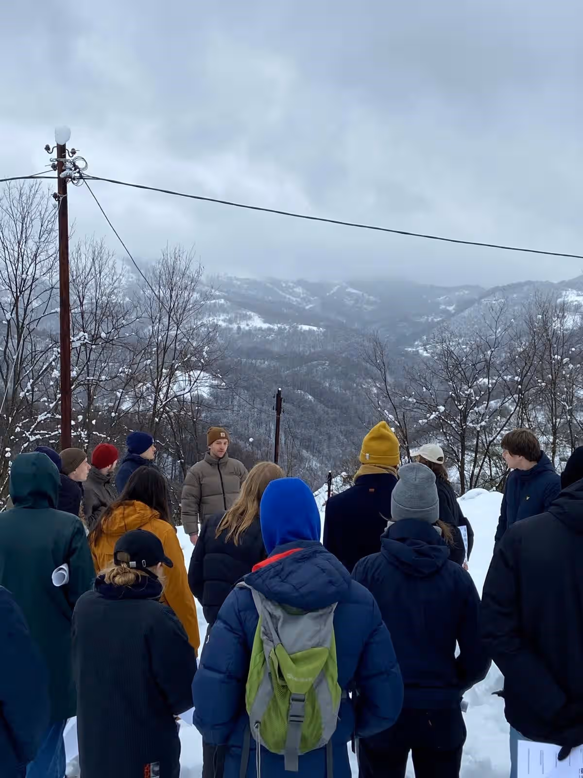 Kleurenfoto. Een groep mensen staat naast elkaar in de buitenlucht. Er ligt sneeuw op de grond.