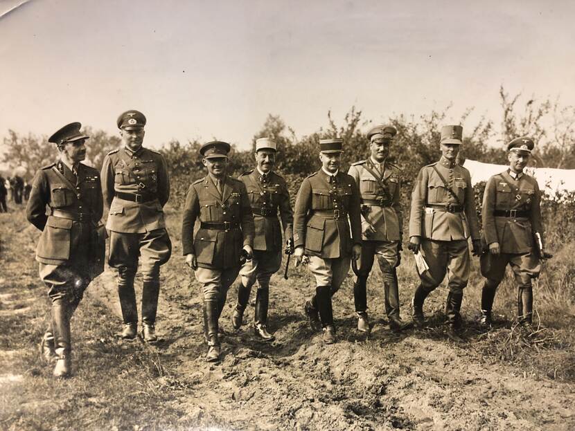 Sepia foto. Groepsportret van wandelende militairen in een landelijke omgeving.