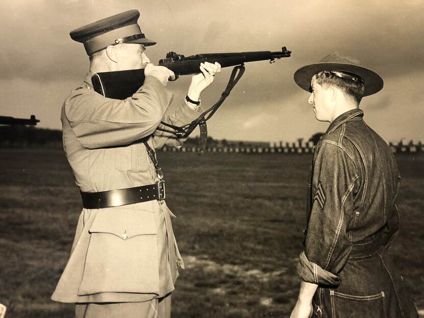 Sepia foto, met links een militair in uniform met een geweer in aanslag.