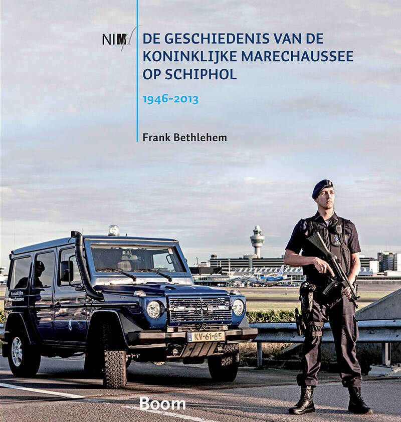 Boekomslag, foto van een marechaussee naast een blauw voertuig van de Koninklijke Marechaussee. Hij houdt een geweer vast. Op de achtergrond is Schiphol te zien met de Schipholtoren en enkele vliegtuigen van KLM. De titel is in blauwe letters gedrukt.