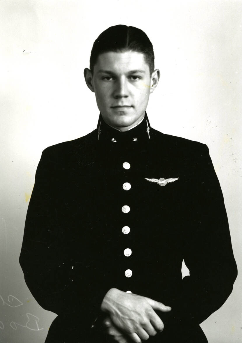 Zwart-witfoto. Portretfoto van een militair, hij draagt een donker uniform met zes grote knopen over zijn borst, zijn handen zitten gevouwen voor zijn buik, op zijn linkerborst draagt hij een speld van een zwaan met uitgespreide vleugels.
