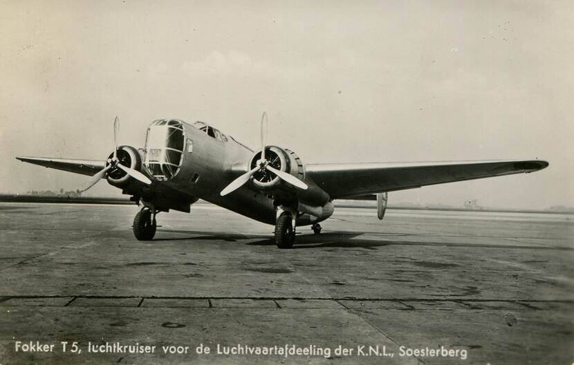 Zwart-witfoto. Een vliegtuig staat stil op een landings- of startbaan, het heeft op elke vleugel een motor met propeller, de neus is groot en van glas. Onderaan de foto staat geschreven dat het om een Fokker T-5 gaat, een luchtkruiser voor de Luchtvaartafdeling op Soesterberg.