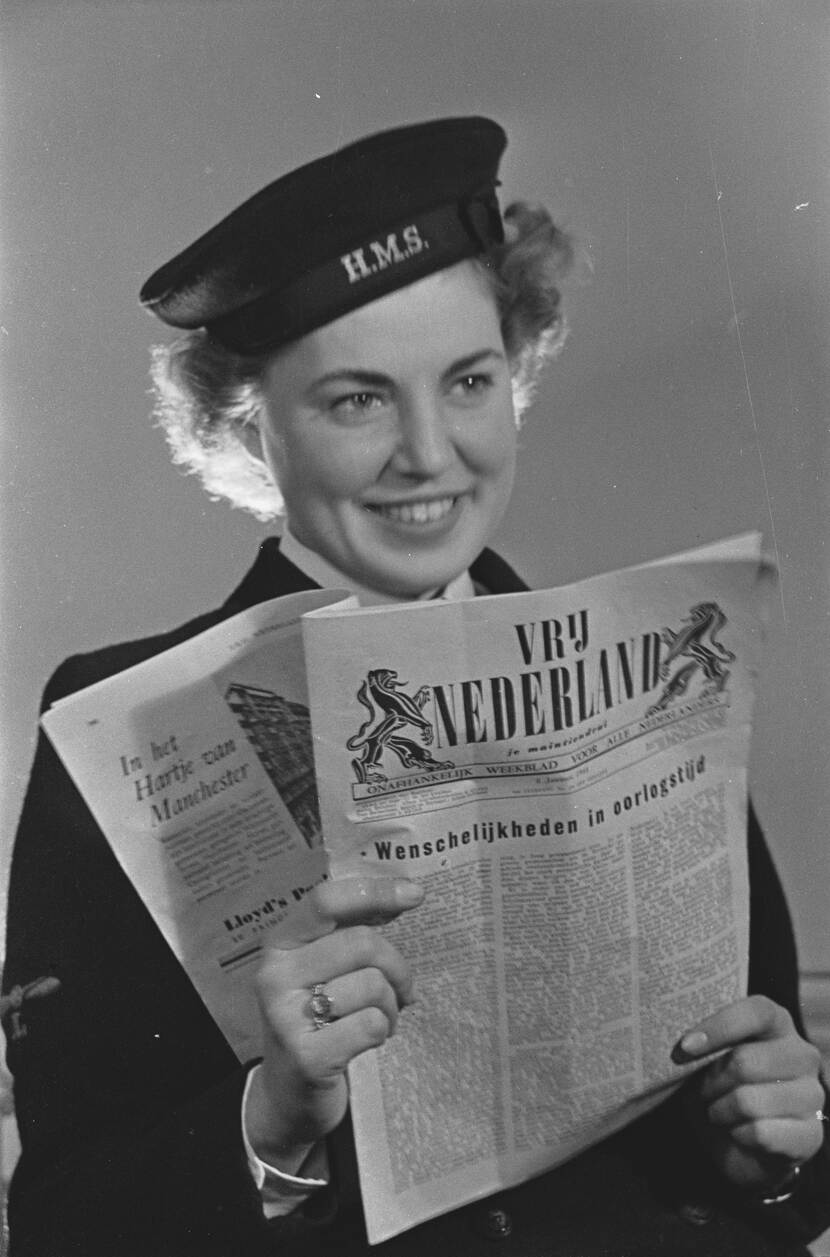 Zwart-witportret van een jonge vrouw in Brits marine-uniform. Ze houdt de krant Vrij Nederland vast.