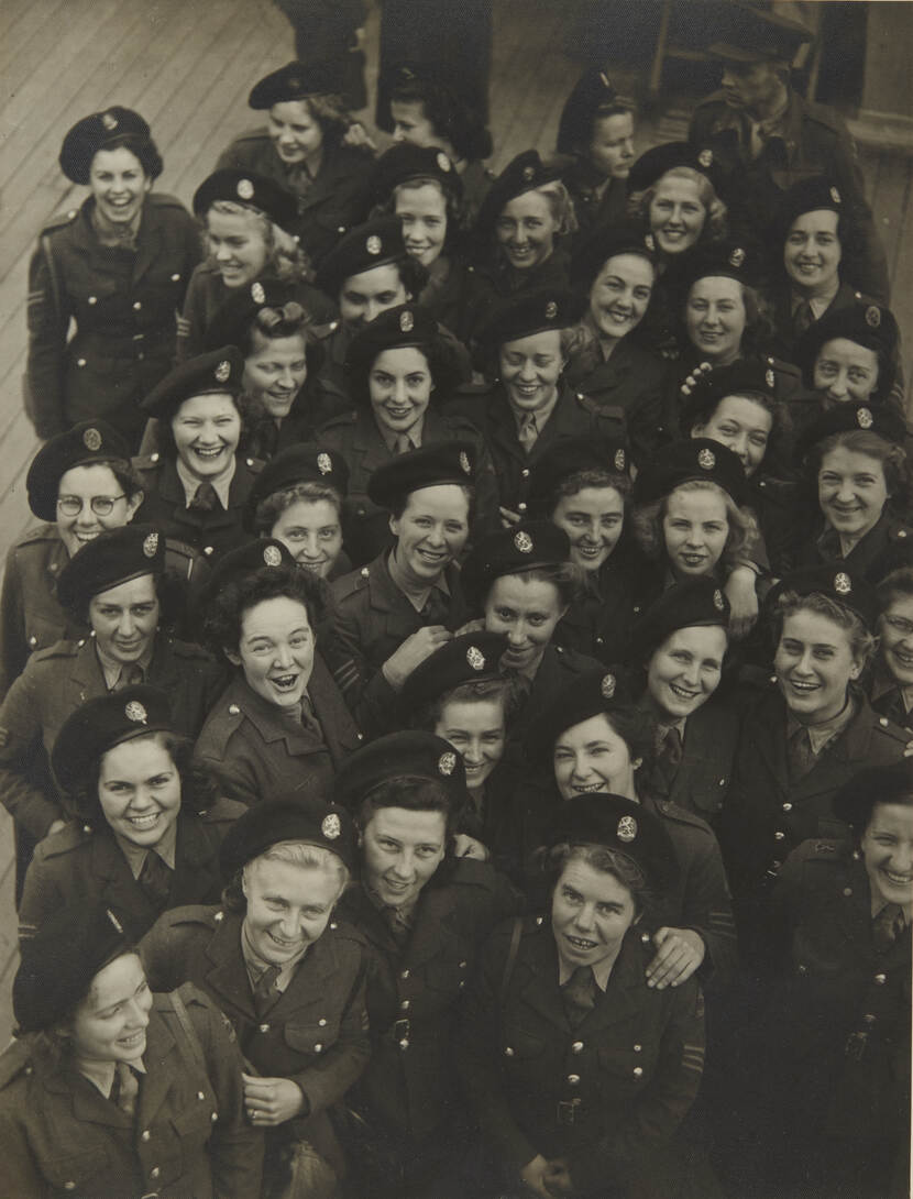 Zwart-witfoto van bovenaf genomen, een stuk of 25 VK-KNIL'sters lacht in de camera.
