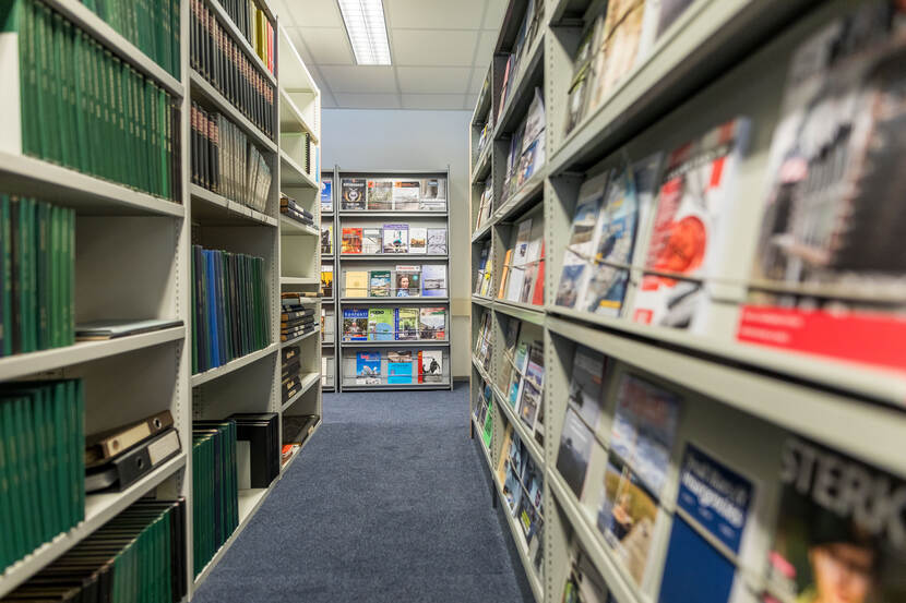 Foto van de bibliotheek in de studiezaal. Links in de stellingkasten staan gebundelde periodieken. Rechts in de kasten tijdschriften.